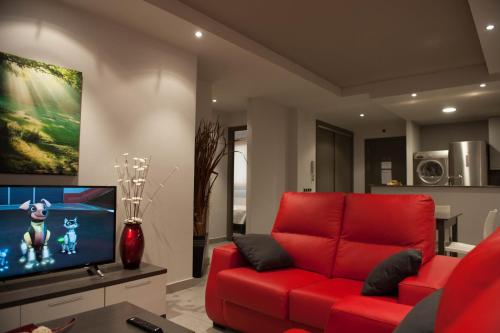 a living room with a red couch and a flat screen tv at WinTuWin Apartments in Rialp