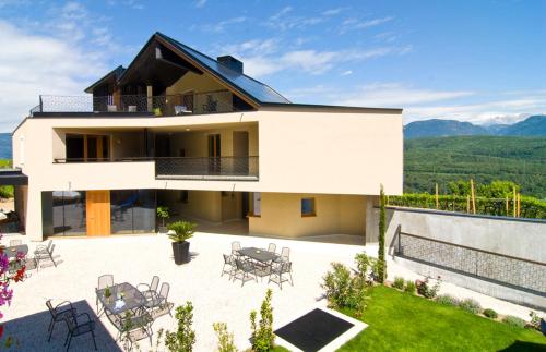 a white house with a patio with tables and chairs at Biobauernhof St. Quirinus in Caldaro