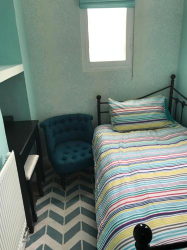 a bedroom with a bed and a blue chair at 2 bed, ground floor Bijou Georgian city apartment in Bath