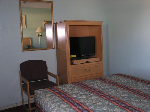 a hotel room with a bed and a tv and a mirror at American Inn Motel in Many