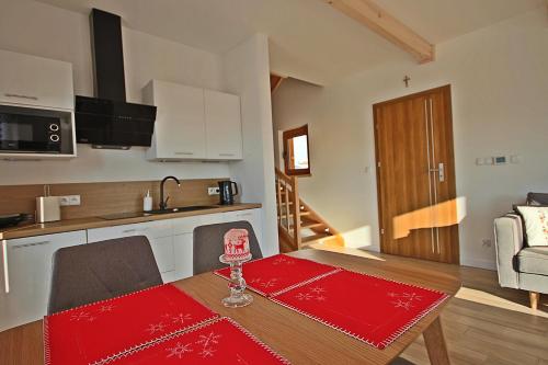 a kitchen with a table with a red table cloth on it at Osada domków Baca in Poronin