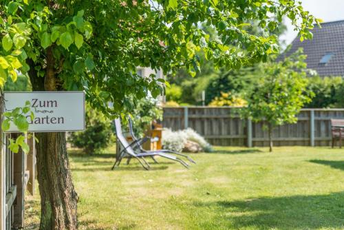 a park bench sitting under a tree in a yard at Ostseehotel Rike in Wismar