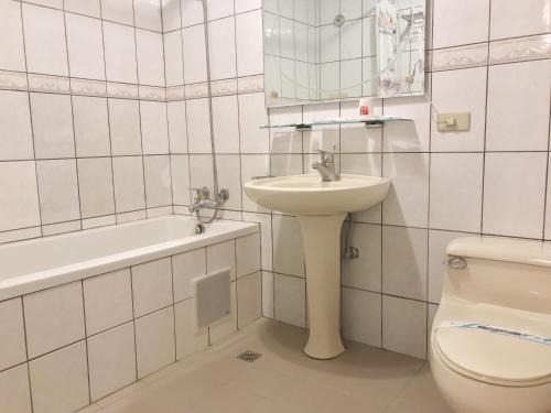a white bathroom with a sink and a toilet at Lidu Hotel in Suao