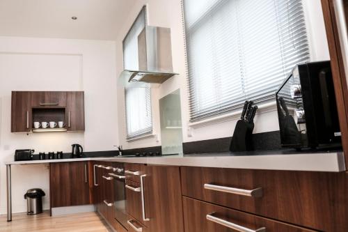 a kitchen with wooden cabinets and a microwave and windows at Four Princes Dock in Hull