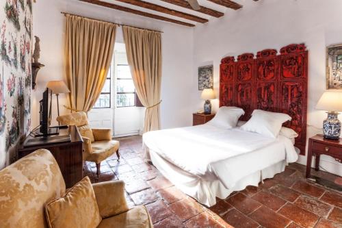 ein Schlafzimmer mit einem weißen Bett und einem Stuhl in der Unterkunft Hotel Spa Salinas de Imón in Imón