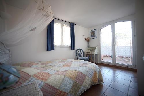 a bedroom with a bed and a desk and windows at B&B Le clos des vignes Saint Raphael in Saint-Raphaël