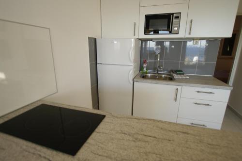 a small kitchen with a refrigerator and a microwave at Murter Inn in Murter