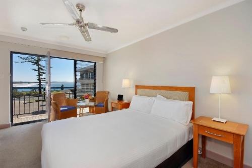 a bedroom with a white bed and a balcony at ibis Styles Port Macquarie in Port Macquarie