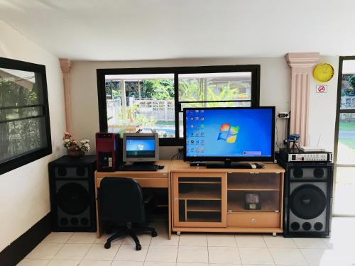 a desk with a computer and two monitors on it at Winter House Chiang Rai in Chiang Rai