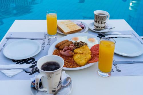 a breakfast table with a plate of food and orange juice at Hera Zakynthos Hotel in Laganas