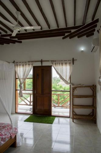a room with a bed and a large window at Shamba Lodge in Nungwi