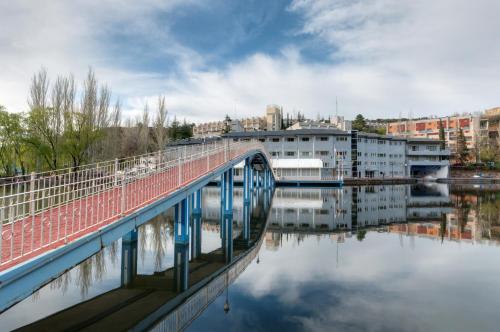 un puente sobre un cuerpo de agua con edificios en Hotel Náyade, en Los Ángeles de San Rafael