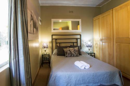 a bedroom with a bed with two towels on it at Merry Pebbles Resort in Sabie