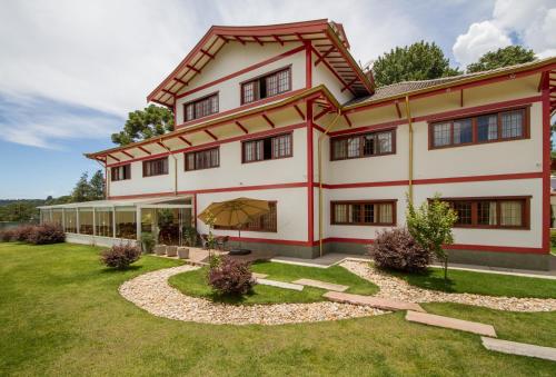 an exterior view of a large house with a yard at Matsubara Pousada in Campos do Jordão