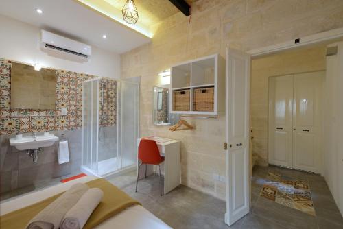 a bathroom with a bed and a sink and a desk at Vallettastay Lovely House Private Rooms in Valletta