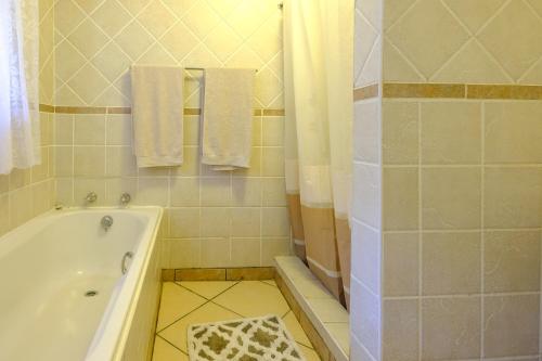 a bathroom with a tub and a shower with towels at St Lucia Palms in St Lucia