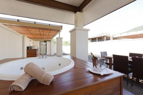 a bathroom with a tub and a table with chairs at Pullman Palm Cove Sea Temple Resort & Spa in Palm Cove