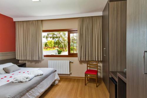 a hotel room with a bed and a window at Matsubara Pousada in Campos do Jordão