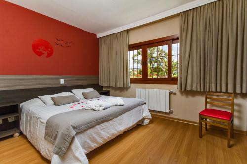 a bedroom with a large bed and a red wall at Matsubara Pousada in Campos do Jordão