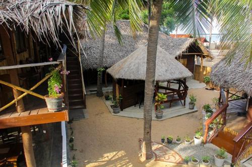 a small hut with a palm tree in front of it at Scoop Cabana Kitesurfing in Kalpitiya