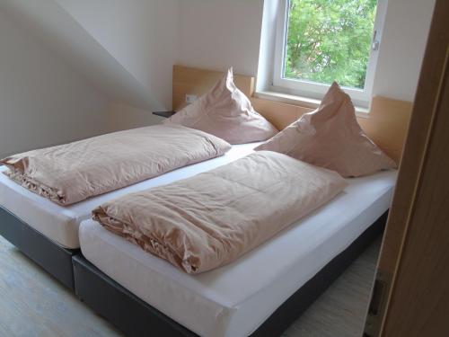 two beds with pillows sitting next to a window at Wein- Appartements Borth in Bretzfeld