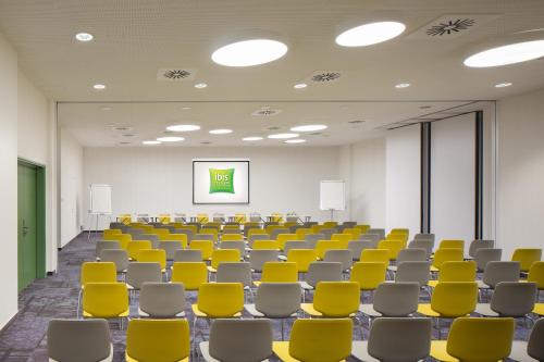 an empty conference room with yellow chairs and a screen at ibis Styles Budapest Airport in Vecsés