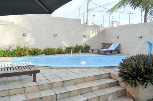 a swimming pool with two benches in a courtyard at Hotel Enseada de Ponta Negra in Natal