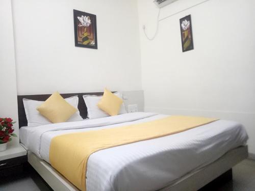Hotel Gopi Palace في أحمد آباد: غرفة نوم بسرير كبير عليها شراشف صفراء وبيضاء