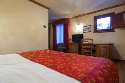 a hotel room with a bed with a red blanket at Hotel Maison Saint Jean in Courmayeur