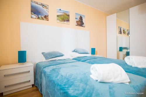 two beds in a bedroom with blue sheets at Baltic in Pogorzelica