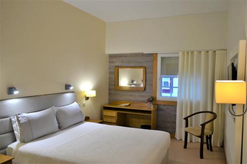 Habitación de hotel con cama y escritorio en Hotel Toural, en Guimarães