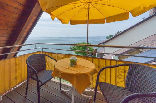 a table and chairs on a balcony with an umbrella at Gästehaus am Bodensee in Immenstaad am Bodensee