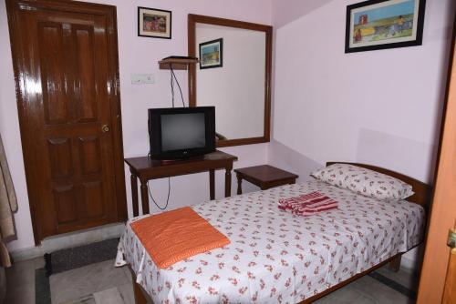 a small bedroom with a bed and a television at anjani mansion in Hyderabad