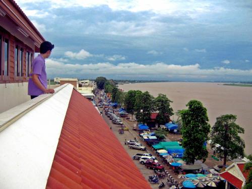 a man standing on a ledge overlooking a harbor at Riverfront Hotel Mukdahan in Mukdahan
