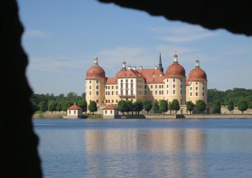 a large building with red domes on the shore of a lake at Hotel garni Sonnenhof in Reichenberg