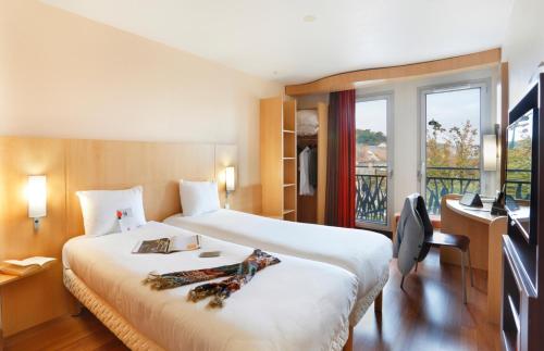 a hotel room with a large bed and a window at ibis Etampes in Étampes