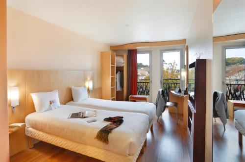 a hotel room with a large bed and a balcony at ibis Etampes in &Eacute;tampes