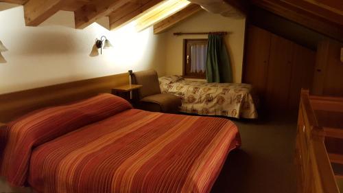 una habitación de hotel con 2 camas y una silla en Villa Zita en Champoluc