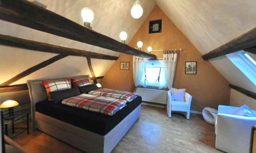 ein Schlafzimmer mit einem Bett und einem Stuhl im Dachgeschoss in der Unterkunft Ferienhaus Gründaublick in Gründau