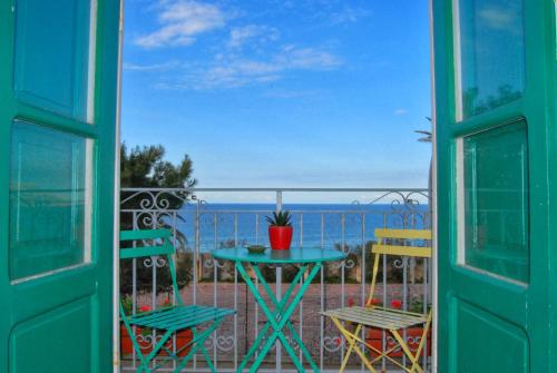 een tafel en stoelen op een balkon met uitzicht op de oceaan bij Le Luminarie - Creative Residence in Balestrate