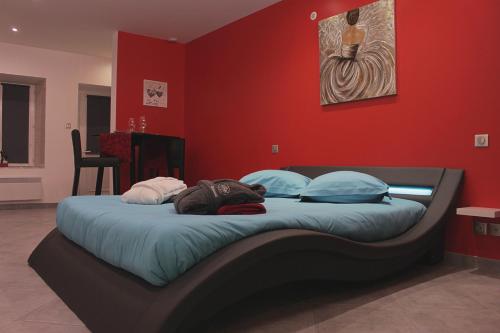 un grande letto in una stanza con una parete rossa di dampierrelove a Dampierre-les-Bois