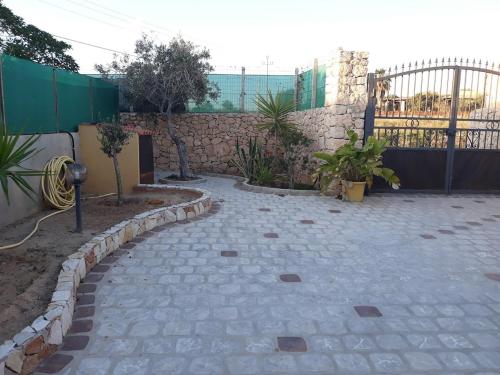 un giardino con un passaggio in pietra e una recinzione di Le casette di Simona a Lampedusa