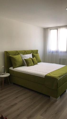 a green bed in a room with a window at Heartland City B&B in Tuzla
