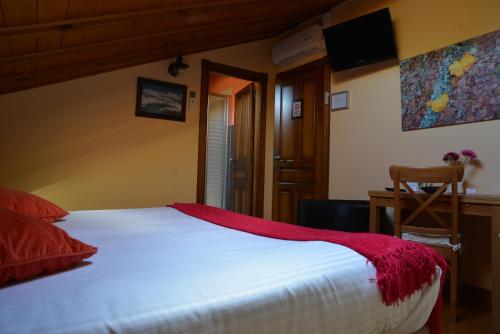 a bedroom with a white bed with a red blanket at Alojamiento Bernabales in Pámanes