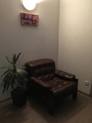 a leather chair and stool in a room with a plant at Rocca Apartments in Tallinn
