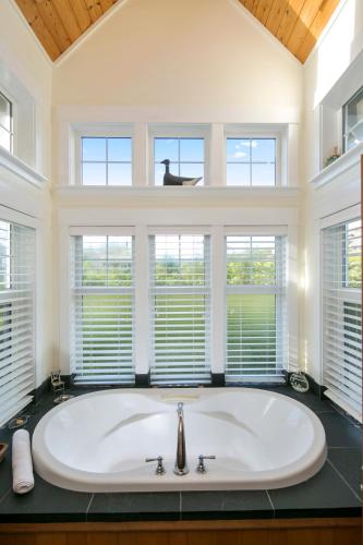 a large white tub in a bathroom with windows at Black Rock Beach House in Ucluelet
