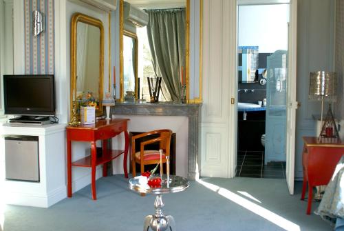 een woonkamer met een televisie en een bureau met een spiegel bij La Gourmandine in Châtellerault
