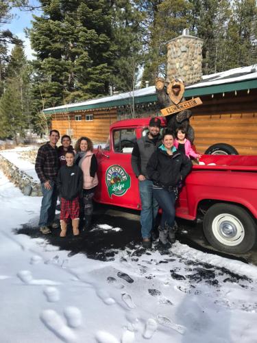 a group of people standing next to a red truck in the snow at Fireside Lodge in South Lake Tahoe