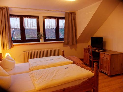 a bedroom with two beds and a desk and windows at Gross Bultener Hof in Peine