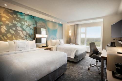a hotel room with two beds and a window at Hotel Dene & Conference Centre in Cold Lake